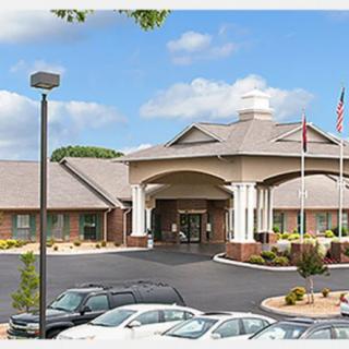 A spacious building entrance with a parking lot and flags displayed outside on a cloudy day.