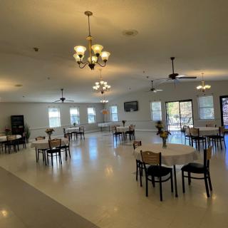 A spacious dining area with neatly arranged tables and chairs, illuminated by chandeliers.