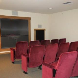 A small home theater room with red chairs and a large screen.