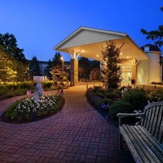 A beautifully lit garden pathway at night with a bench and well-maintained landscaping.