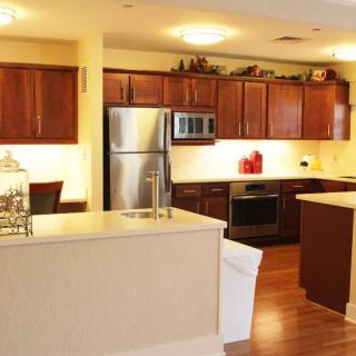 A modern kitchen with wooden cabinets and stainless steel appliances, featuring an island counter in an open-plan design.