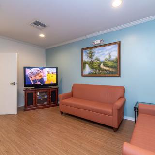 A cozy living room with two couches, a television, and a painting on the wall.