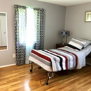 A simple bedroom with a single bed, striped bedding, and hardwood floors.