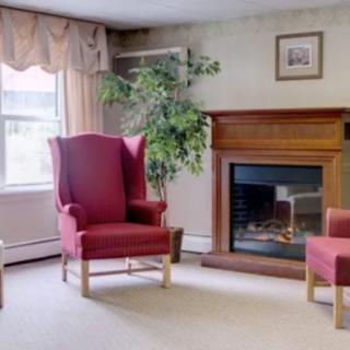 A cozy living room with a fireplace, red chairs, and a large window.