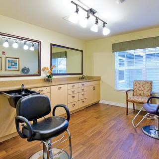 A well-lit hair salon interior with a styling chair, mirror, and sink.