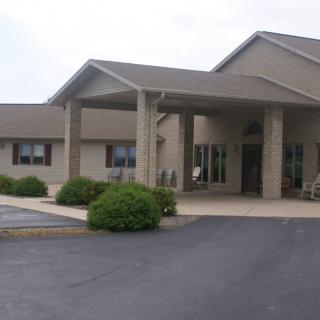 A suburban building with a covered entrance and a parking lot in front.