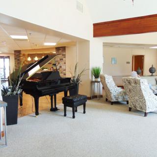 A modern lobby interior featuring a grand piano and a comfortable seating area.