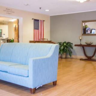 A cozy living room with a light blue sofa and an American flag on the wall.