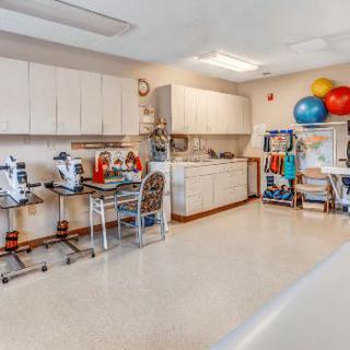 A spacious physical therapy room equipped with various exercise machines and tools for rehabilitation.