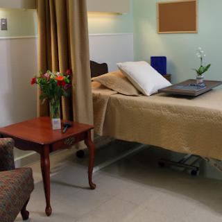 A serene hospital room featuring a bed, a small table with flowers, and comfortable seating.
