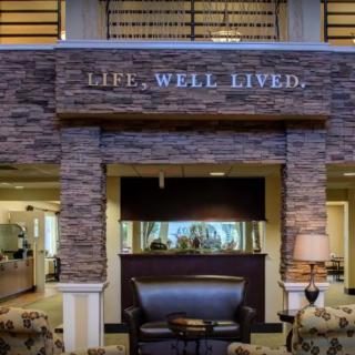 A cozy seating area with a stone wall and aquarium under the phrase 'Life... Well Lived.'