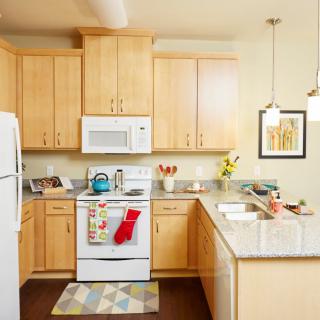 A modern kitchen with wooden cabinets, white appliances, and decorative touches.