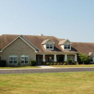 A suburban house with a large lawn and driveway under a clear sky.