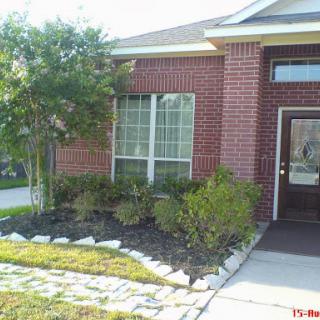 A well-maintained front yard showcasing a brick house with attractive landscaping.
