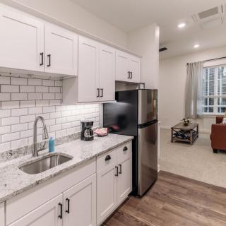 A modern kitchen with white cabinets and subway tile backsplash, opening to a cozy living room.