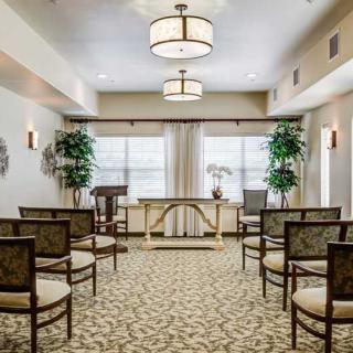 A neatly arranged ceremony room with chairs, plants, and soft lighting.
