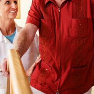 A healthcare professional assists an elderly person in physical rehabilitation.