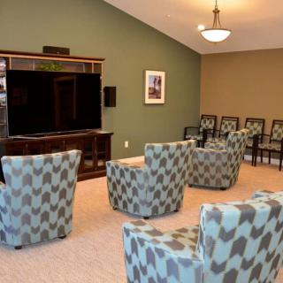 A cozy seating area with patterned chairs facing a large television in a modern living room.