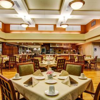An elegant dining room with neatly arranged tables and chairs, featuring soft lighting.