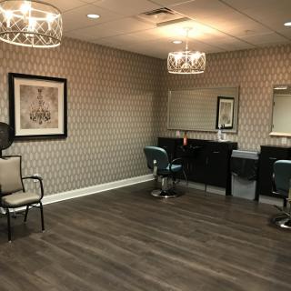 A modern salon interior featuring stylish chairs, large mirrors, and elegant lighting.