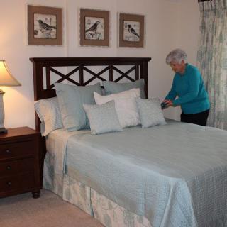 A person is making a neatly arranged bed in a cozy and well-decorated bedroom.