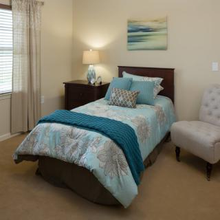 A cozy bedroom with a single bed, decorative bedding, and soft lighting.