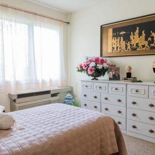 A cozy bedroom with a dresser, floral arrangement, and wall art.