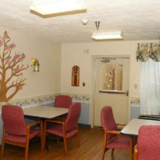 A cozy dining room with tables and chairs, decorated with wall art and soft lighting.