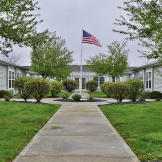 A landscaped courtyard with a central pathway leading to a building, featuring an American flag.