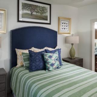 A cozy bedroom featuring a bed with striped bedding, decorative pillows, and framed artwork on the walls.