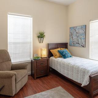 A cozy bedroom with a single bed, armchair, and decorative elements.