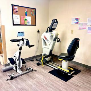 A fitness area featuring a recumbent bike and a seated exercise machine, designed for rehabilitation and low-impact workouts.