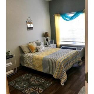 A cozy bedroom with colorful bedding and a decorative window.