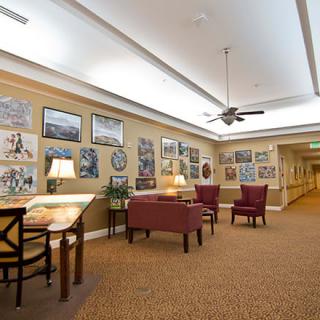 A cozy hallway featuring seating with artwork adorning the walls, illuminated by lamps.