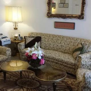 A cozy living room with floral-patterned furniture, a brass coffee table, and a decorative mirror.