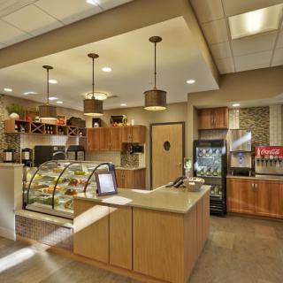 A modern cafe interior with a counter, display case, and seating area.