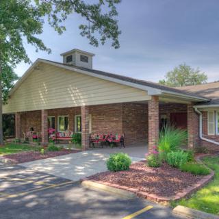 A welcoming exterior of a residential building showcasing landscaped grounds and a cozy front entrance.