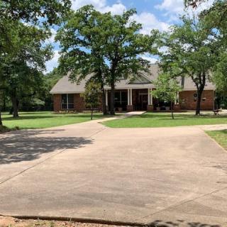 A suburban home with a spacious driveway surrounded by trees on a sunny day.