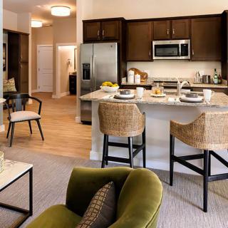 A modern kitchen and living area featuring a spacious layout with bar stools at the counter and contemporary appliances.