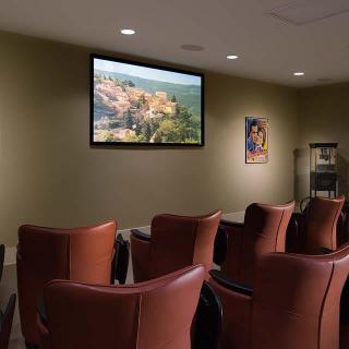 A cozy waiting room with comfortable chairs and a television screen displaying an image.