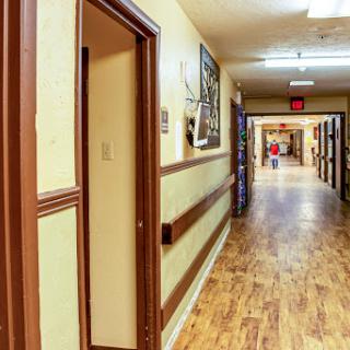 A well-lit hallway with wooden flooring and artwork on the walls.