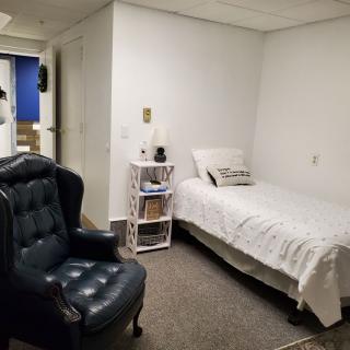 A cozy bedroom with a single bed and a comfortable armchair.