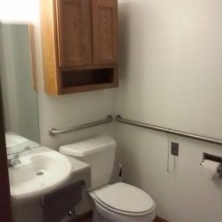 A small bathroom with a sink, toilet, and wooden cabinet.