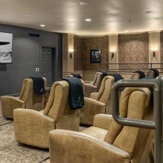 A cozy movie theater room with comfortable beige recliner seats arranged in rows.