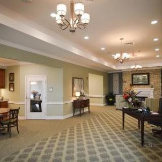 A spacious and well-lit living room with elegant furniture and chandeliers.