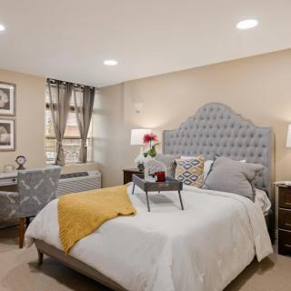 A cozy and well-decorated bedroom with a tufted headboard, stylish bedding, and bedside lamps.