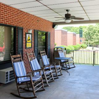 A serene porch setup featuring rocking chairs and a ceiling fan, perfect for relaxation.