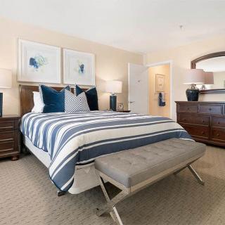 A well-decorated bedroom with a striped bedspread, elegant furniture, and tasteful artwork.