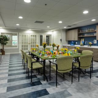 A modern dining room with a long table set for a meal, featuring stylish chairs and a decorative centerpiece.
