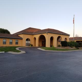 A welcoming yellow building with arches and a manicured landscape.